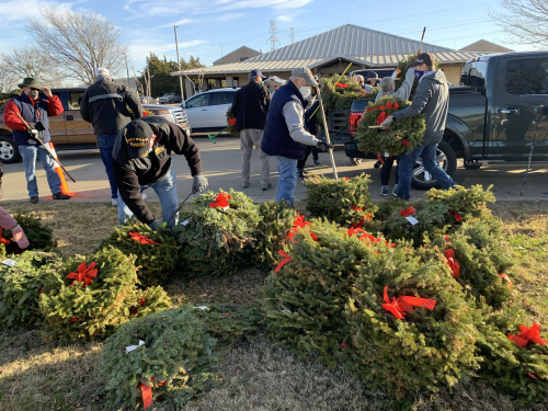 Removing the wreaths from the gravesites and loading them on trucks for disposal.
